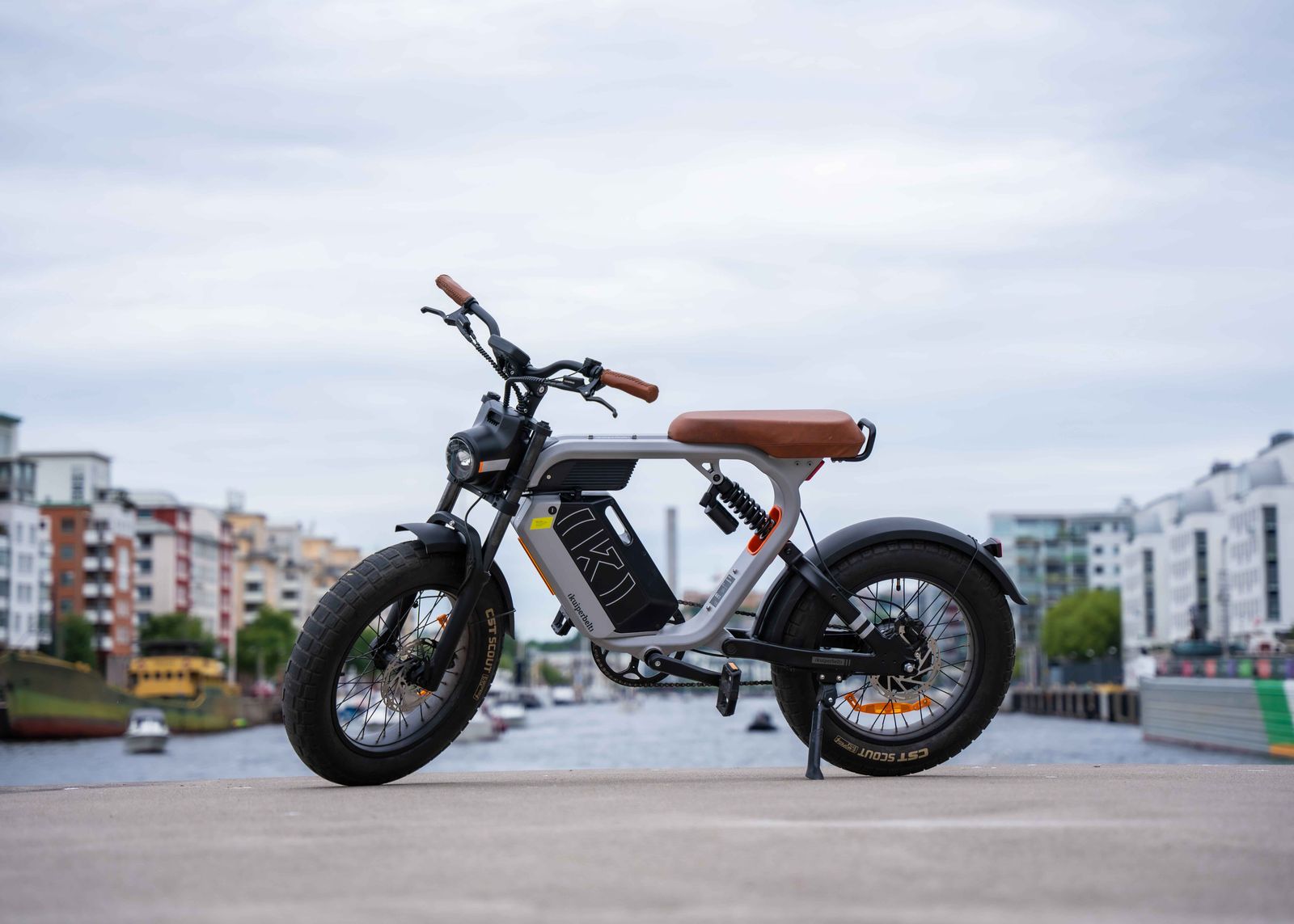 Kuiperbelt S1 elcykel med brun sadel och tjocka däck, parkerad vid vattnet i Stockholm